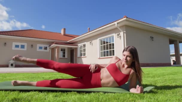 Joven Mujer Caucásica Haciendo Levantamientos Piernas Laterales Con Hermosa Casa — Vídeo de stock