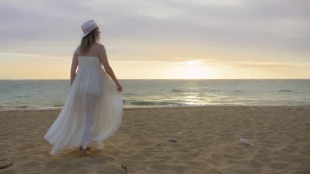 海のビーチの人々 黄金の夕日を歩いて幸せな女性のシルエット 夢の結婚式のコンセプトで幸せな花嫁 海の上で美しい夕日を楽しむ空気中で手を上げている女性の背景ハワイ — ストック動画