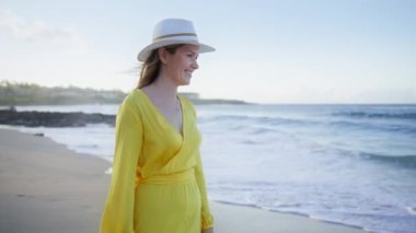 Okyanus esintisinde sallanan parlak yazlık elbisesiyle güzel, seksi, gülümseyen bir kadının ağır çekim portresi. Havai adasında mavi okyanus dalgalarına bakan muhteşem bir kızın portresi.