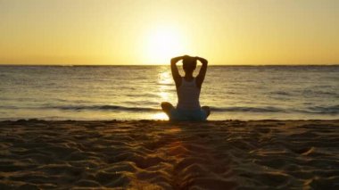 Altın yaz günbatımında Lotus 'un önünde poz veren Yogi kızı. Sağlıklı yaşam tarzı, açık hava meditasyonu, doğa eğitimi, rahatlama ve zen konsepti çekimi. Kızıl Kamerada Manzaralı Kumsal