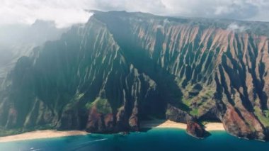 Vahşi mavi okyanus sahilindeki yeşil ve kırmızı garip şekilli tepelerin inanılmaz manzarası. Açık hava macerası. Sinematik Hawaii doğa manzaraları. Güzel volkanik dağ sırtları olan NaPali sahili
