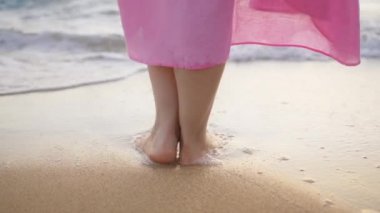 Yaz günbatımında mavi okyanus suyuna karşı narin dişi bacaklarını kapat. Okyanusun sığ sularında kalan, güneşlenen, doğanın tadını çıkaran bir kız. Yavaş çekim RED kamera yaz tatilini çekti