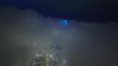 San Francisco şehir merkezindeki şehir sokaklarının gece aydınlanmasıyla ortaya çıkan sis. Siste manzaralı şehir manzarası. Bulutların üzerinde yükselen modern şehir gökdelenlerinin nefes kesici hava manzarası