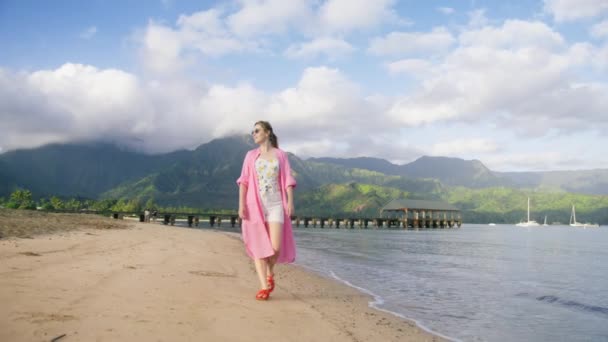 映画のような高い緑の山を背景に熱帯ハワイ島の空の砂浜を歩く無料の女性 夏休みの夢のコンセプト アウトドア旅行を楽しむ幸せな無料旅行者 Usa — ストック動画