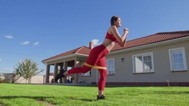 Kadın vücudunun alt ve bacak kaslarını geliştirmek için etkin bir şekilde eğitiyor. Kadın sporcu direniş için elastik bant kullanıyor. Yüksek kalite 4k görüntü