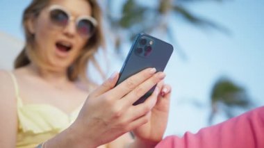 Tatilde akıllı telefon cihazıyla cep telefonu tutan mutlu beyaz kadın. Gülümseyen genç blogcu kadın yeni sosyal medyaya abone oluyor, internetten alışveriş yapıyor, seyahat rezervasyonu yapıyor, uygulamalarla oteller kuruyor