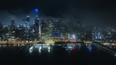 San Francisco şehri gece aydınlandı, şehir merkezindeki sisli şehrin üzerinden uçtu. Gece yıldızlarının altında havadan iniş panoraması 4K. San Francisco gecesi finans binaları şehir merkezinde yükselişte