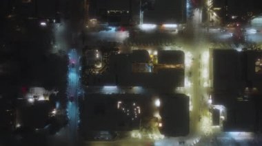 Gece aydınlığıyla kış caddelerinin üzerinden uç. Sokak ışıkları ve küçük kasaba trafiği, gece drone kuşları görüntüsü, Colorado. Aspen kasabası, kış zamanı kar manzaralı gece manzaralı.