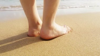 Yaz tatilinde destansı bir plaj. Yaz yüzme aktivitesi. Güneşli yaz gününde çıplak ayaklı bir kadın Hawaii 'de tatilin tadını çıkarıyor. Düşük açılı kırmızı kamera hala ıslak kumsalda çıplak ayakla kadınları çekiyor.