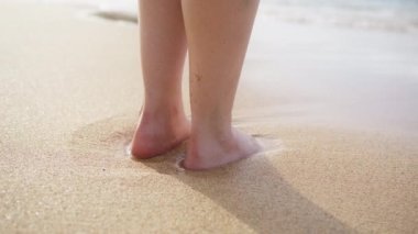 Girl feet and legs in soft water waves. Slim female legs on seafront. Water splashes on golden sandy beach in slow motion. Perfect woman legs on seashore enjoy summer vacation shot on RED camera