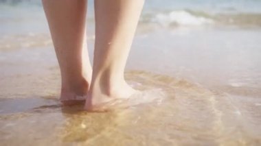 Low angle RED camera still shot of women bare feet on wet sandy beach floor. Epic beach on summer vacation. Summer swimming activity. Barefoot woman on sunny summer day, enjoying holidays on Hawaii