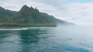 Havai tropikal adasının sinematik ve el değmemiş doğası ile çekilmiş görüntüleri. Aktif turistler, Hawaii 'nin Napali kıyısındaki Haena plajında kürek çekerek eğleniyorlar. Yüksek kalite 4k görüntü