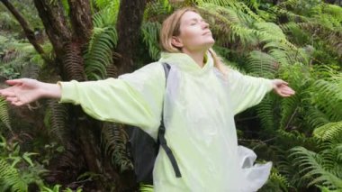 Özgür Mutlu Yürüyüş Kadını, temiz yağmurluklarıyla kollarını kaldırarak yağmur ormanlarında temiz hava soluyor. Eğreltiotu rüzgarda esiyor. İnsan Ormanı. Özgürlük Mutluluğu