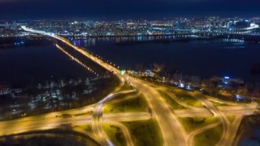 Aerial footage of the vibrant illumination of the buildings facades during twilight. Hyperlapse shot over the lively wharf with heavy traffic along the bridge. High quality 4k footage