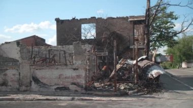 Mart 2022. Irpin, Ukrayna. Barışçıl küçük kasabadaki sivil sanayi bloğu füzelerle yok edildi. Yol kenarında araçları ve yayası olan havaya uçurulmuş bir bina. Yüksek kalite 4k görüntü