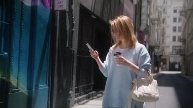 Şehir Caddesinde, günlük kıyafetler giyen, akıllı telefon kullanan güzel beyaz kadın portresi. Insanlarla Bağlanan Seyahat Blogcusu, San Francisco ABD 'de İnternet Taraması, Mayıs 2022