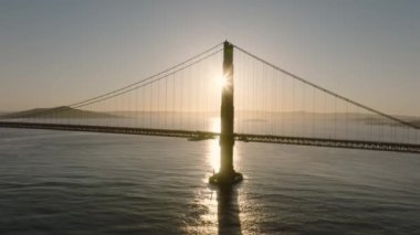 Golden Gate Köprüsü 'nün havadan görüntüsü San Fransisco' nun altın gün doğumunda. Dünyanın en ünlü süspansiyonu Golden Gate Köprüsü 'nün arkasında arka planda parlayan sinematik altın güneş ışığı sabahın erken saatlerinde, Kaliforniya ABD 4K