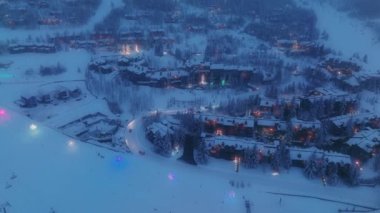 Büyülü kış, Noel köyü manzarası. Aydınlanmış dağlık alp şehri, karla kaplı, beyaz dağlar, kayak merkezi Aspen tatil köyü, 4K gecesi. Kış gecesi dağlar, hava manzarası.