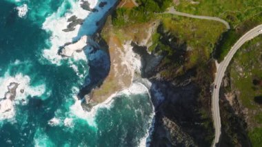 Beautiful nature of California West Coast, USA. Car driving on windy mountain coast road by scenic Bir Sur shore. 4K aerial top down view above vehicle. Road number 1 Americans main beautiful road