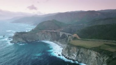 Pacific Ocean rocky coastline Scenic Area is a famous tourist attraction on Big Sur shore, Bixby bridge. Aerial footage of beautiful mountain natural scenery in California at sunset, West Coast of USA