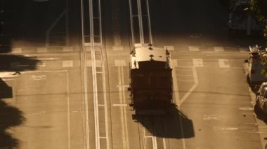 Cinematic slow motion silhouette of tourist landmark attraction tram in California. Historic retro cable car riding up the hill in San Francisco city on early weekend morning in golden sunlight glow