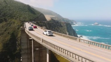 Aerial close up of Pacific Coast highway above Big Creek Bixby Bridge in Northern California with cinematic ocean coast views on sunny summer holiday. Commercial travel background with copy space 4K
