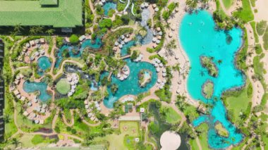 Travel to luxury resort hotel on paradise island. Tourist people relaxing at blue swimming pools, enjoying exotic tropical nature at hotel spa with beach views and green palm trees. Scenic lagoon pool