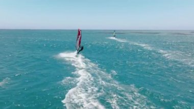 Jul. 2022. California, USA. Rider performing extra speed and power by the sail catching the wind. Drone footage of wave sailors surrounded by spectacular summer seascape. High quality 4k footage