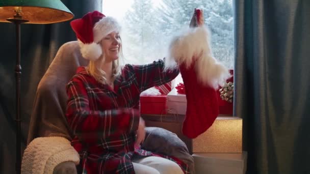 Щаслива Жінка Санта Капелюсі Притягує Подарунок Панчіх Застряглих Затишна Кімната — стокове відео