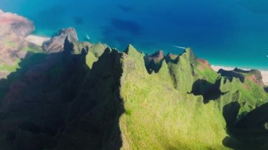 4K drone shot white bird flying above scenic breathtaking mountain tops with impressive weird green peaks on blue ocean panorama background.Sunrise view of Napali coast park on Kauai island Hawaii USA