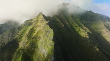 Spectacular aerial view of Napali coast Mountains in Kokee park, on top of Kauai ancient volcano, scenic Hawaii island in USA. Beautiful clouds covering green peaks of mountain ridge on sunny morning