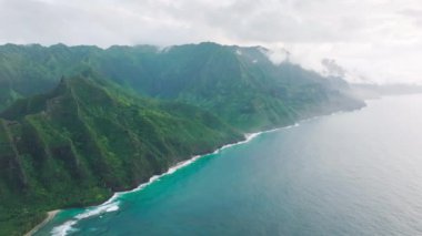 Panoramic aerial of scenic Kauai nature. Cinematic green summit landscape of wild island nature USA. Incredible deep blue ocean waves crashing at high green mountains with steep tropical jungle peaks