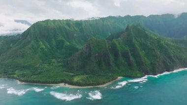 Incredible deep blue ocean waves crashing at high green mountains with steep tropical jungle peaks. Panoramic aerial of scenic Hawaii nature. Cinematic green summit landscape of wild island nature USA