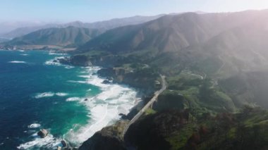 Drone footage of coastal wilderness in Big Sur, California. Road trip along Pacific shoreline with mountains in the background. High quality 4k footage
