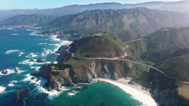 Scenic highway along the cliff edges of Big Sur. An aerial view of magnificent setting at Bixby Canyon below foggy skyline. High quality 4k footage