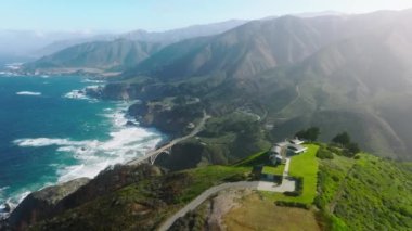 An aerial footage of mesmerizing Pacific Ocean coastal area. Stunning surroundings of Bixby Creek Bridge with morning fog above the mountains. High quality 4k footage