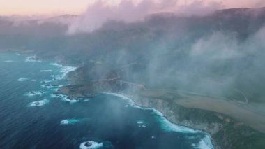 Drone footage over outstanding beauty of adventurous tourist destination with coastal landscape. Cloudy purple skyline above cinematic ocean and greenish forests. High quality 4k footage