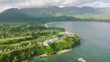 Cinematic Princeville shore with summer beach cottages and oceanfront villas on scenic Hawaii landscape background. Summer vacation in paradise 4K drone. Aerial Hanalei Bay villas on Kauai island 4K