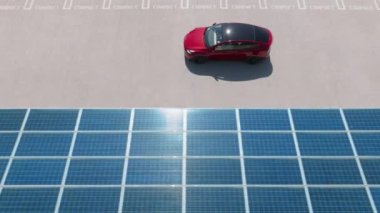 Aerial view red car driving along parking lot with solar panel roof. 4K zero pollution car, green energy concept at city parking lot. Alternative energy for ecological cars under blue solar batteries