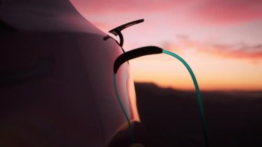 Close up of generic electric car charging with cinematic pink sunset on background. Green and renewable energy concept. 3d animation with blue beam of energy flowing through cord into vehicle socket