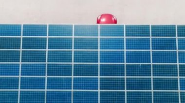 Generic red electric car driving by electric vehicle charging station under blue solar panel batteries at rooftop parking lot. Zero emission vehicle at EV only charging station on sunny summer day 4K