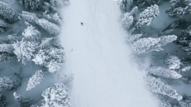 Winter outdoor activities. Winter sports and recreation, winter tourism vacation, Christmas holidays. Slow motion aerial footage of skier skiing on ideal ski slope in big mountains below drone camera