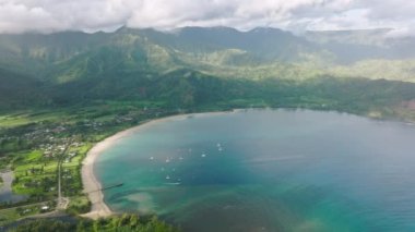 A panoramic shot of the Hanalei Bay with lavish rainforest and steep mountains. Aerial view of a tourist destination for a tropical dream vacation. High quality 4k footage