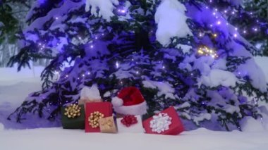 Cozy outdoor Christmas atmosphere. Snow falling from glowing Christmas tree on stack of colorful gift boxes left by Santa Claus as surprise present. Spirit of magical Christmas and New Year background