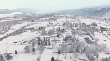 Drone flying above small village farms and houses with winter mountain landscape background, 4K Colorado nature. Aerial view small countryside village Carbondale town on cold sunny winter day
