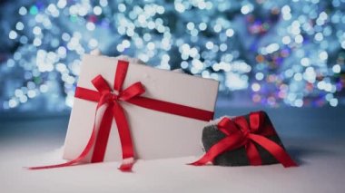 Cinematic animation of shiny sparkling Merry Christmas message handwritten on beautiful Christmas background with elegant black and white gift boxes in red satin ribbon. Happy new year 2023 background
