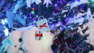 Sihirli Kış geçmişi. Mutlu Noel arifesinde karlı köknar dalında güzel hediyelerle geçen kış görüntüleri. Sürpriz mavi hediye çantası ve Noel ağacında kırmızı saten fiyonklarla hediye paketi.