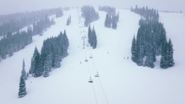 Soğuk kış gününde, Colorado 'nun Aspen bölgesindeki Kar kitlesi kayak merkezinde Noel tatili. Kış turizmi havadan 4K görüntüsü. İnsanlar tepeden kayak sandalyeleri ve manzaralı köknar ormanlarıyla kayak yapıyor.