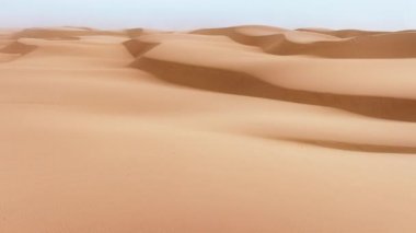 Rüzgârın oluşturduğu büyük kum kütlesinin havadan görünüşü. Mavimsi, berrak ufuk çizgisinin altında sıradışı bir kumul sisteminin muhteşem manzarası. Yüksek kalite 4k görüntü