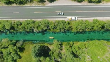 Güneşli yaz gününde, erkek yüzme suyunun 4K 'lık havadan inişi bisiklet taşımacılığı, orman yolu boyunca ayak kontrolü. Parlak sarı pedallı teknede kürek çeken bir adam. Nehir kıyısındaki su aktivitesinde turist
